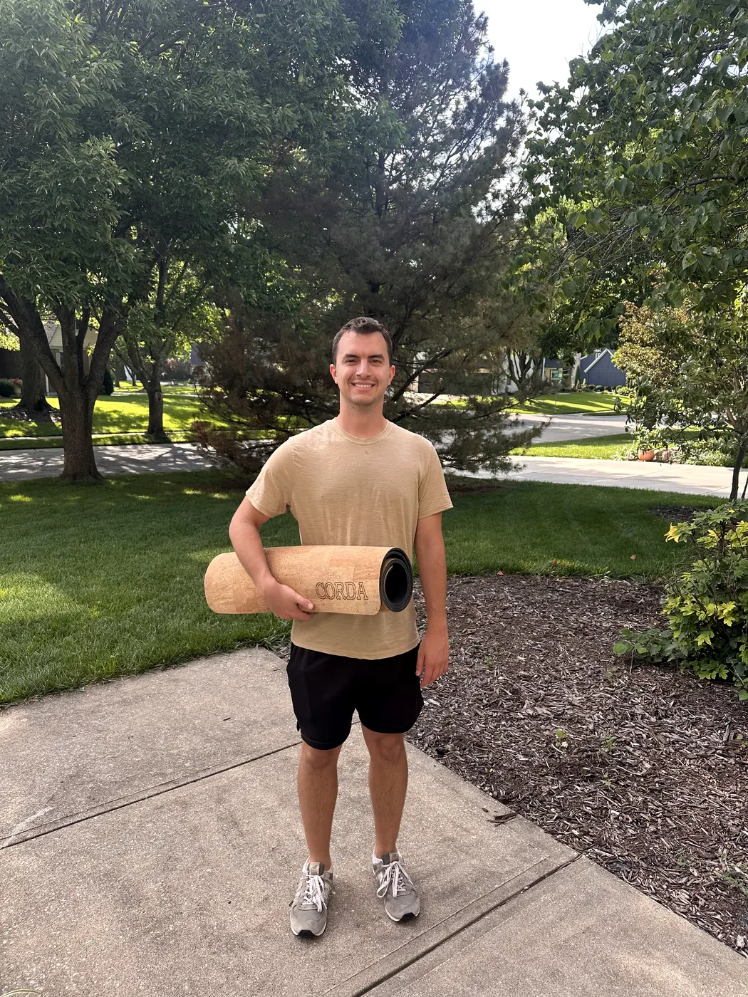Gage outdoors holding a rolled Corda cork mat under one arm