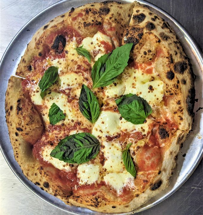 A whole margherita pizza on a wooden cutting board